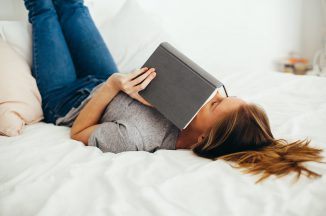 Girl lying on bed holding book